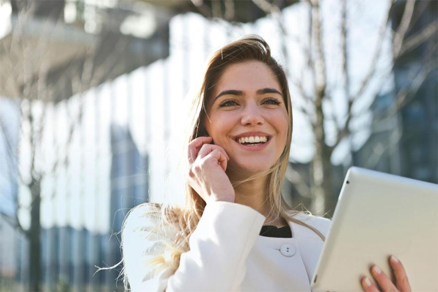A Young lady smiling while holding an iPad in her hand